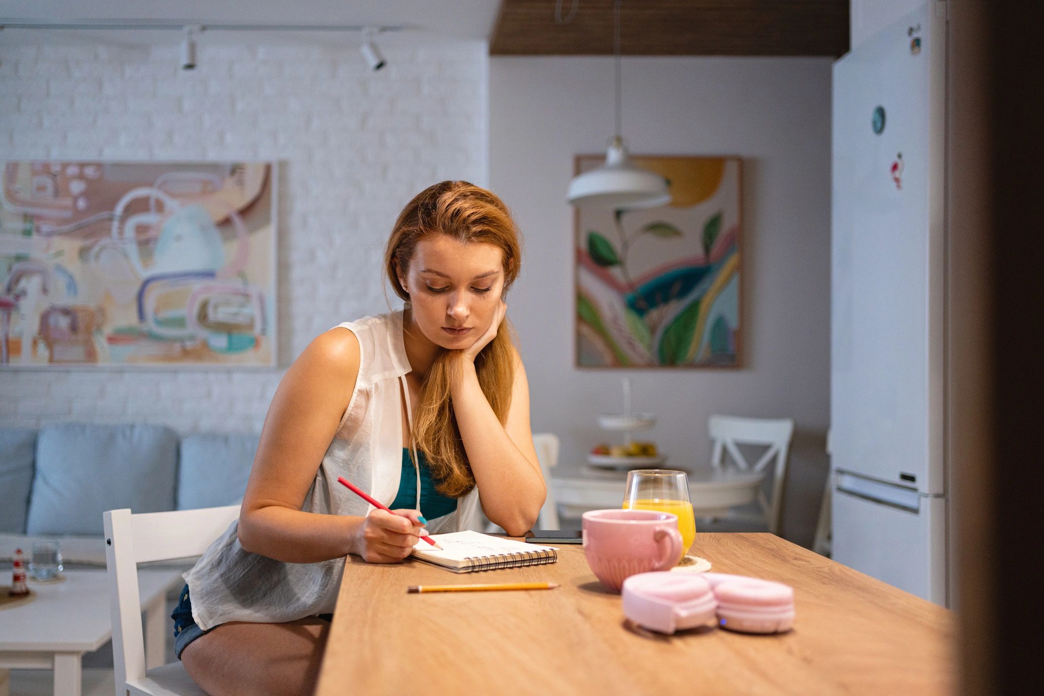 Woman writing in a notebook at a kitchen counter