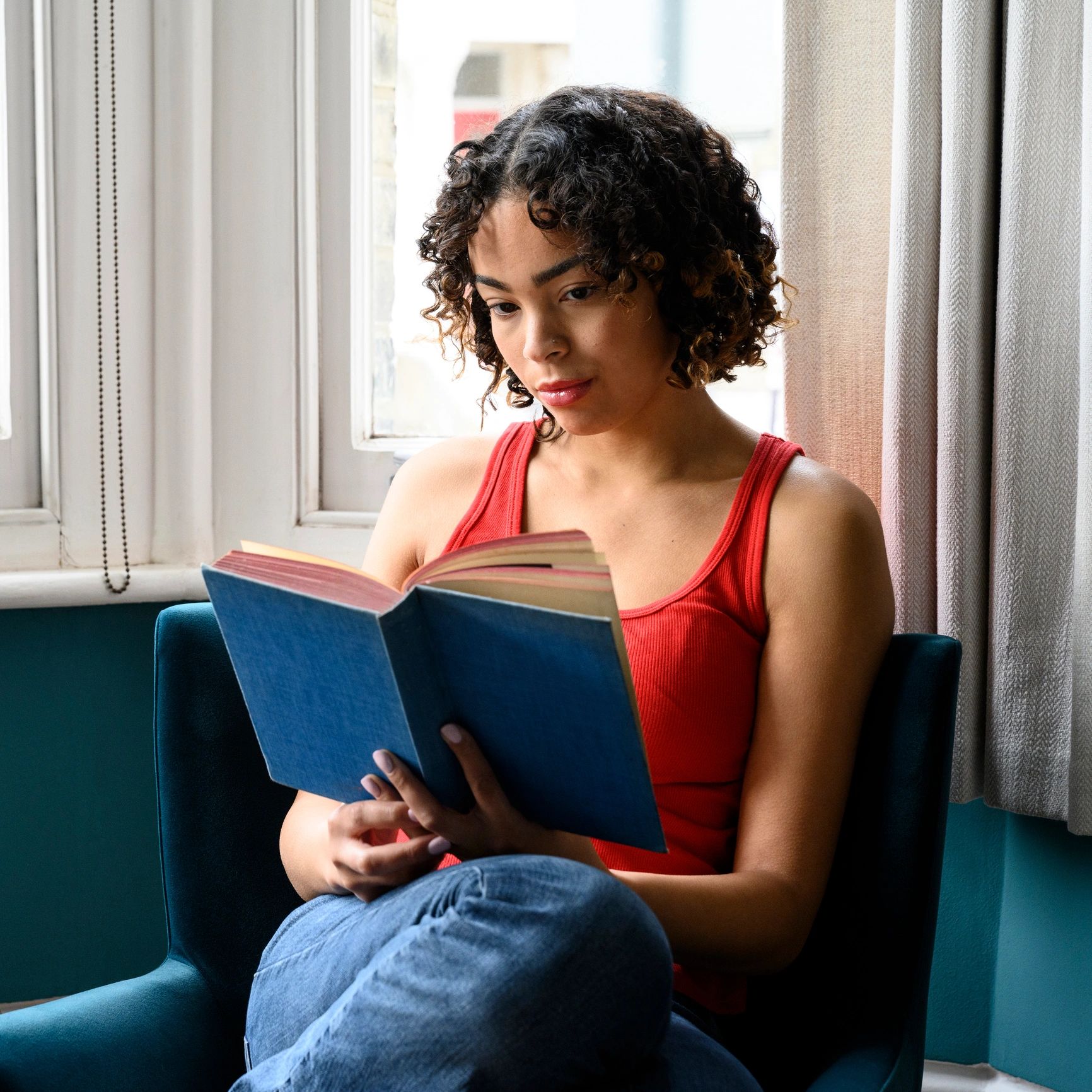 Person reading by a window at home, calm and reflective.