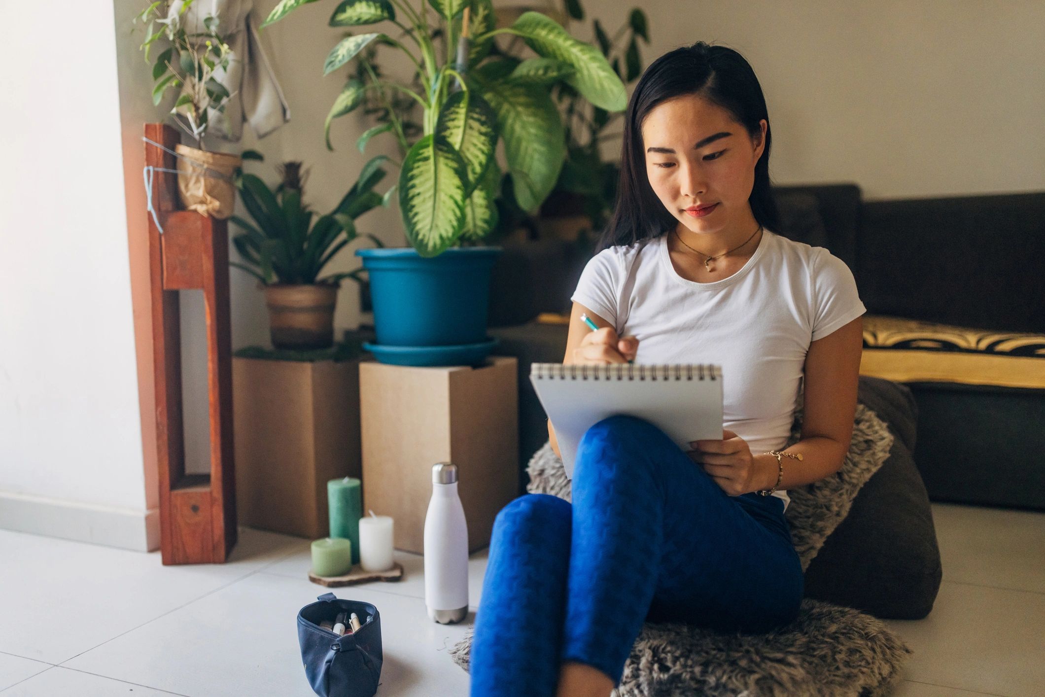 Woman drawing in a notebook while seated on the floor