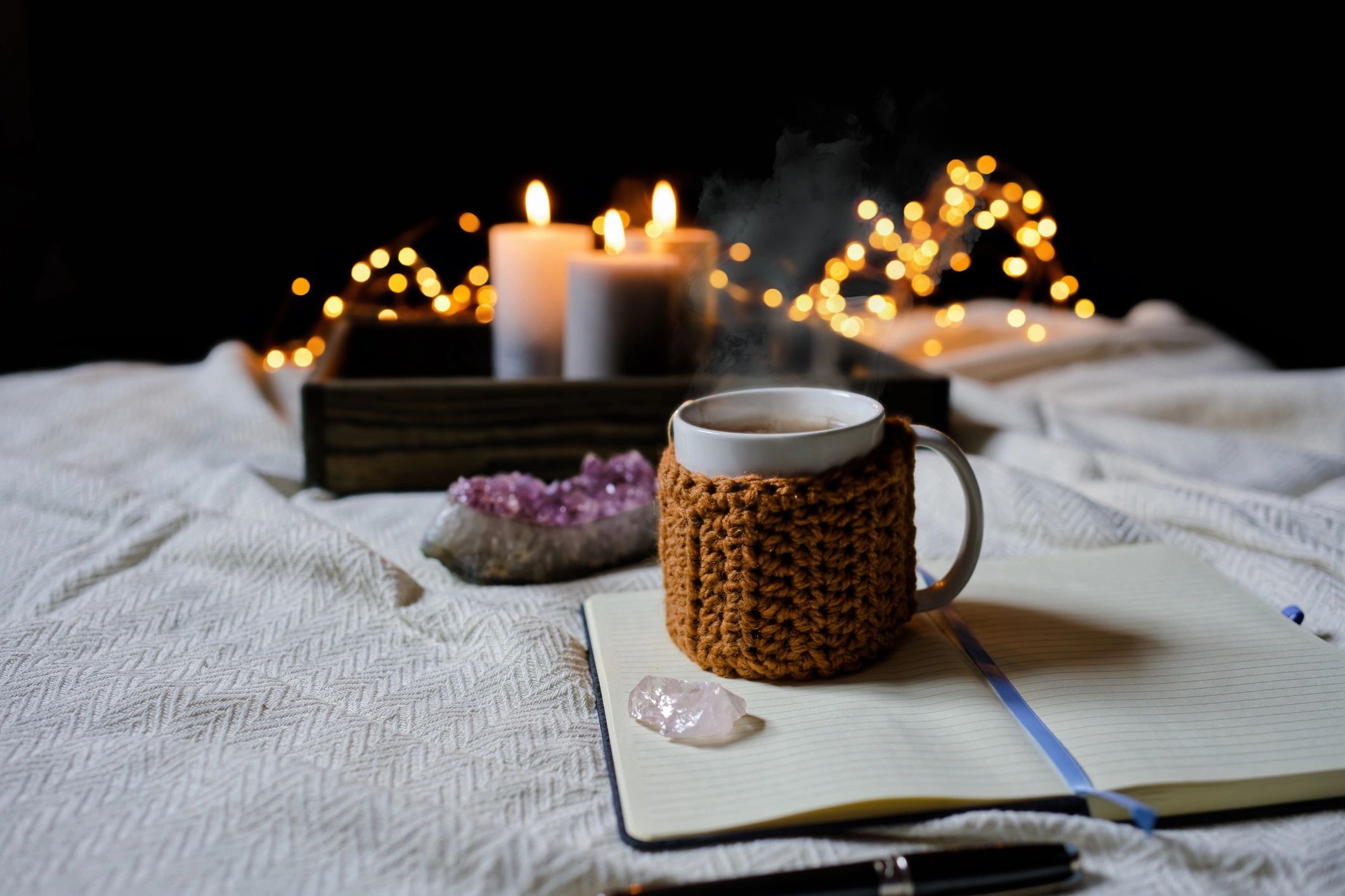 Open notebook beside warm tea and crystals in soft candlelight