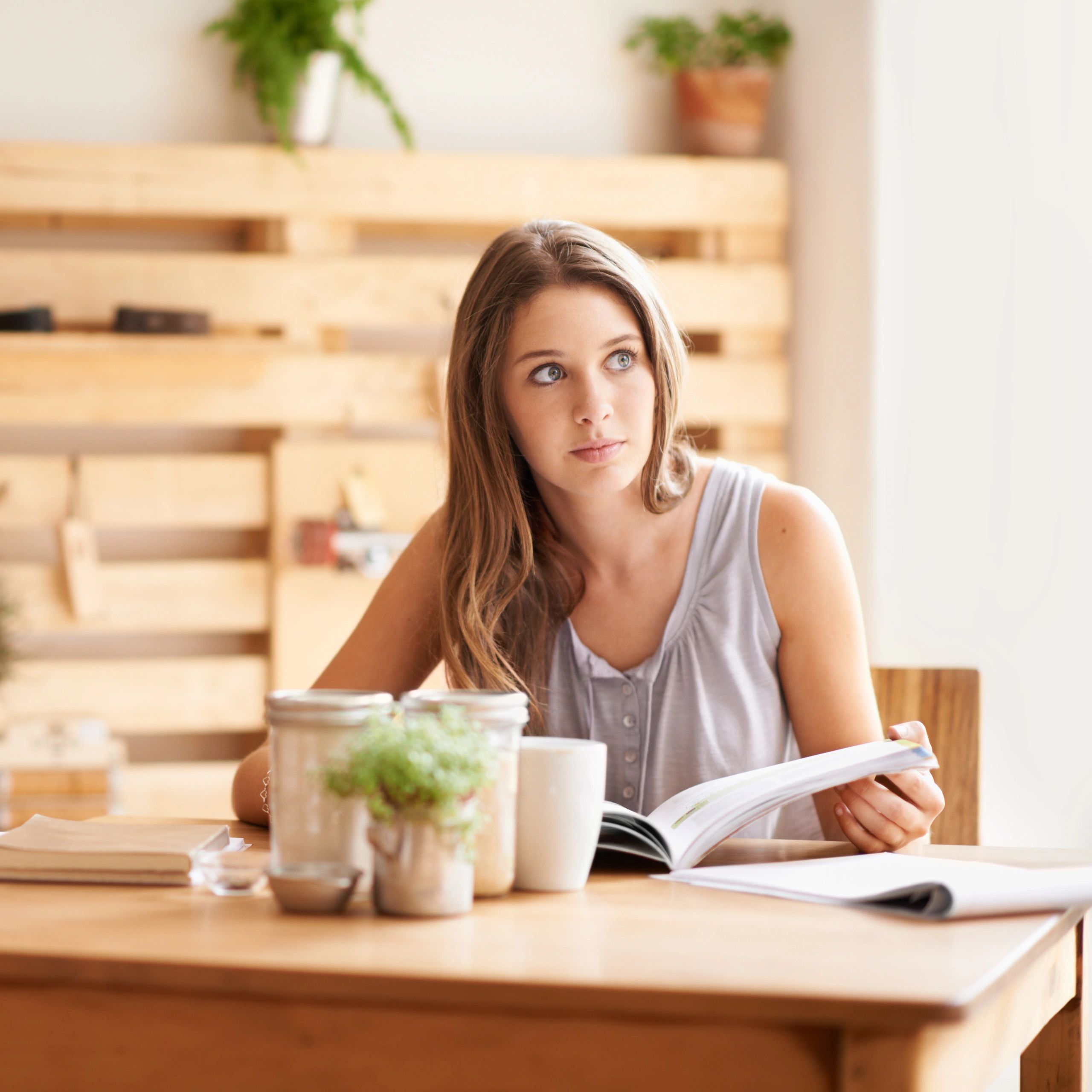 Person reading and reflecting with a book and coffee.